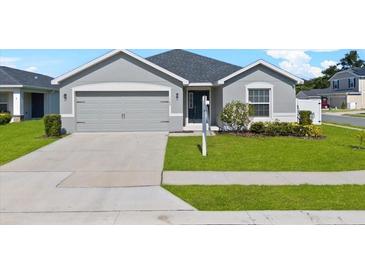 Charming single-story home with a well-manicured lawn and a two-car garage in a suburban neighborhood at 1106 Tropea Ln, Auburndale, FL 33823
