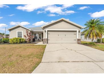 Charming single-story home with a well-manicured lawn, gray exterior and a two-car garage in a residential neighborhood at 2700 Oak Hammock Loop, Mulberry, FL 33860
