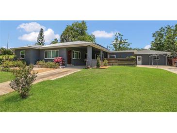 Charming home featuring a spacious front yard and a covered porch, complemented by lush landscaping and mature trees at 317 S 8Th St, Haines City, FL 33844
