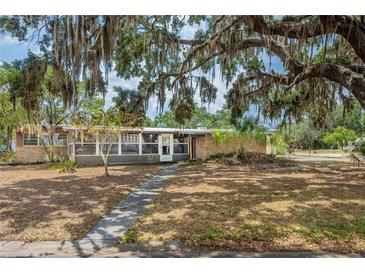 Charming one-story brick home featuring an inviting front yard with mature trees and a sidewalk at 415 Manor Dr, Bartow, FL 33830