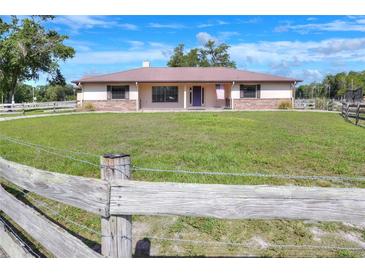 Charming single-story home with a metal roof, brick accents, a fenced yard and a vibrant green lawn at 4404 Musket Dr, Lakeland, FL 33810