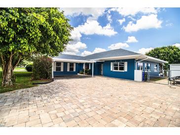 Charming blue home features a brick driveway, carport, and well-maintained landscaping at 1328 Edgewater Beach Dr, Lakeland, FL 33805