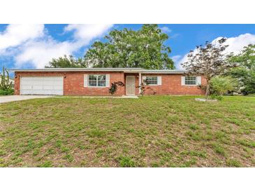 Charming brick home featuring a well-manicured lawn, attached garage, and traditional windows at 1507 Neptune Dr, Lakeland, FL 33801