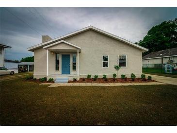 Charming single-story home with well-maintained lawn, garden bed and a vibrant blue front door at 208 Center St, Auburndale, FL 33823