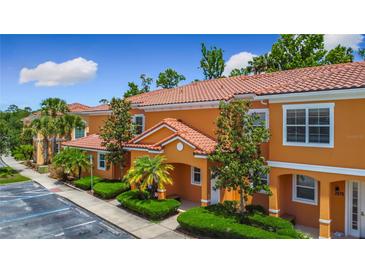 Charming condo with a Spanish tile roof, orange stucco, mature landscaping, and assigned parking at 2683 Corvette Ln, Kissimmee, FL 34746