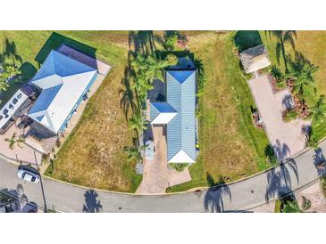 An aerial view of a charming home with a blue metal roof, lush landscaping, and brick-paved driveway at 3016 Wood Duck Dr, Polk City, FL 33868