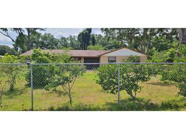 Ranch-style house with a charming tan exterior, well-maintained lawn, and mature trees around the property at 5211 Berkley Rd, Auburndale, FL 33823