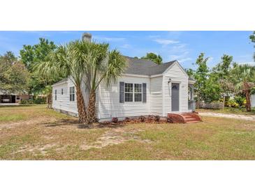 Charming home featuring a well-kept lawn and a white exterior, complemented by vibrant palm trees at 725 Avenue B Sw, Winter Haven, FL 33880