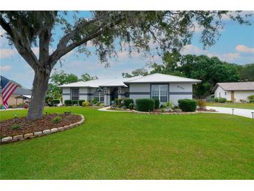 Charming single-story home with a manicured lawn, mature tree, and welcoming curb appeal on a sunny day at 8760 Plantation Ridge Blvd, Lakeland, FL 33809