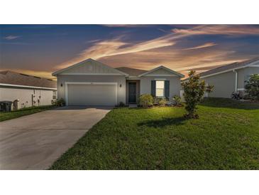 Charming single-story home with neutral siding, attached garage, and manicured lawn under a colorful sky at 1725 Hill Top Dr, Dundee, FL 33838
