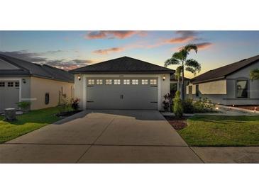 Two-car garage with decorative details and palm trees in a well-maintained front yard during dusk at 2293 Caspian Dr, Lakeland, FL 33805