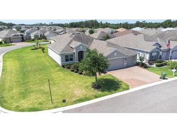 Aerial view of single-story home showcases its well-kept lawn, landscaping, and brick driveway leading to a garage at 3136 Langdon Ln, Winter Haven, FL 33884