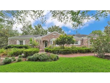 Charming brick home with manicured lawn, lush landscaping, and a welcoming front entrance at 323 E Belvedere St, Lakeland, FL 33803