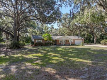 Charming single-story brick home featuring a well-manicured lawn and mature trees, creating a serene and inviting curb appeal at 5624 Laurel Oak Dr, Lakeland, FL 33811