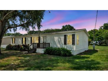 Charming single-story home with white siding, black shutters, front porch, and mature trees on a green lawn at 5751 Cherry Tree Dr, Lakeland, FL 33811