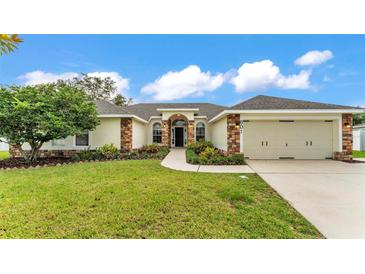 Charming single-story home features a well-manicured lawn, lush landscaping, and an attached two-car garage at 601 Pintail Cir, Auburndale, FL 33823