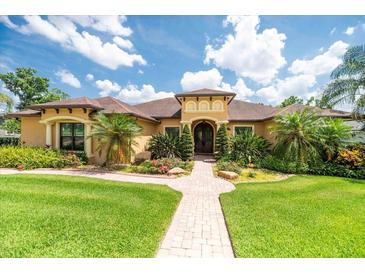 Inviting home with manicured lawn and beautiful landscaping, featuring a brick walkway to the front door at 6357 Ashley Dr, Lakeland, FL 33813