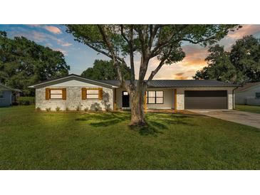 Charming single-story home featuring a well-manicured lawn, painted brick, and a sleek black roof at 6543 Tula Ln, Lakeland, FL 33809