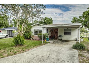 Charming single-story home with a covered carport, inviting front yard and beautiful landscaping at 102 Pike St, Auburndale, FL 33823