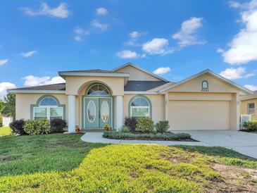 Charming home exterior with landscaped yard, double door entry, and attached two-car garage at 2255 Couples Dr, Lakeland, FL 33813