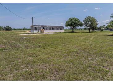 Single-story home featuring neutral siding, black shutters, and a large, grassy yard at 246 Quail Run, Frostproof, FL 33843