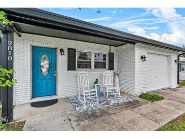 Charming front porch with a blue door, white rocking chairs, and brick exterior, offering a cozy entrance at 2810 Gary Ln, Lakeland, FL 33812