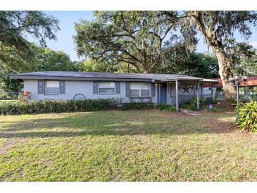 Charming single-story home featuring a covered porch, mature trees, and a well-manicured lawn at 2920 Audie Combee Rd, Lakeland, FL 33801