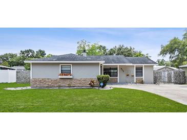 Charming single-story home showcasing a well-manicured lawn and gray facade with stone accents at 417 El Salvador Dr, Lakeland, FL 33809