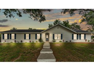 Charming single-story home with white siding, blue shutters, a manicured lawn, and a concrete walkway at 4825 Foxrun, Lakeland, FL 33813