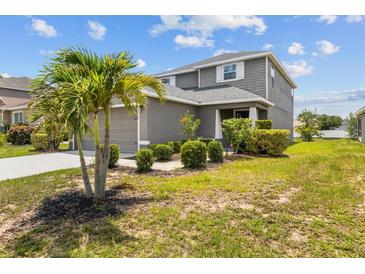 Charming two-story home with a manicured lawn and vibrant landscaping featuring a palm tree at 2850 Sanderling St, Haines City, FL 33844