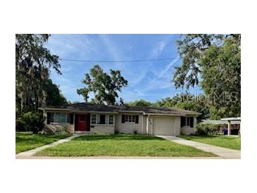 Charming single-story home featuring a red front door, well-maintained lawn, and an attached one-car garage at 1215 E Edgewood Dr, Lakeland, FL 33803