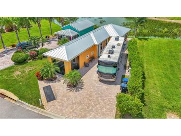 Aerial view of a charming yellow home with a paved driveway and a large RV parked alongside it at 3261 Fish Hawk Dr, Polk City, FL 33868