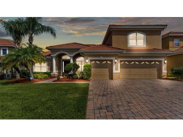 Charming tan two-story home with a brick driveway, lush lawn, and well-maintained landscaping at 3980 Sunset Lake Dr, Lakeland, FL 33810