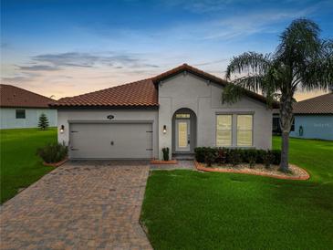 Charming single-story home featuring a tile roof, arched entryway and lush landscaping at 4125 Prima Lago Cir, Lakeland, FL 33810