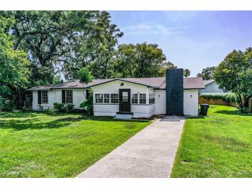 Charming single-story home with white exterior, black trim, chimney, and lush green lawn at 4629 Harden Blvd, Lakeland, FL 33813