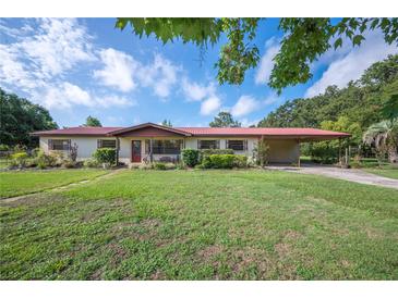 Ranch style home with a red metal roof, a covered car port, and a well-maintained lawn at 5140 Alderman Rd, Lakeland, FL 33810
