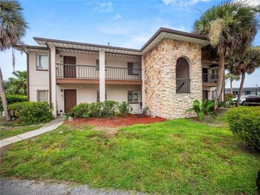 Two story home with stone accent, balconies, brown trim, green lawn, and mature palm trees at 803 Orchid Springs Dr, Winter Haven, FL 33884
