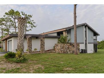 Charming home featuring a stone wall, pillars, manicured lawn, and a two-car garage at 102 Canterbury Dr, Haines City, FL 33844