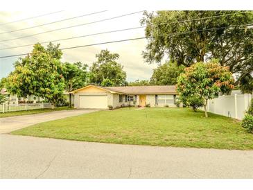 Charming single-story home with a well-manicured lawn, mature trees, and an attached one car garage at 111 Beverly Dr, Winter Haven, FL 33884