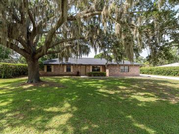 Charming brick home with a well-maintained lawn and mature trees draped with Spanish moss in a quiet neighborhood at 1315 Costine Dr, Lakeland, FL 33809