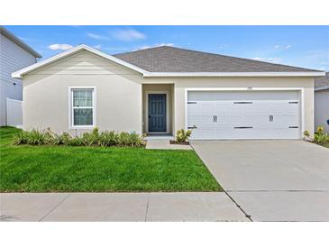 Charming single-story home featuring a well-maintained lawn, attached garage and neutral stucco at 1371 Madison Cir, Haines City, FL 33844