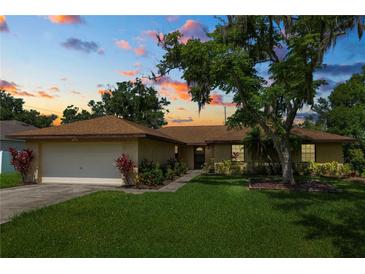 Charming one-story home featuring a well-manicured lawn, mature tree, and attached two-car garage at 1917 Lori W Ln, Lakeland, FL 33801