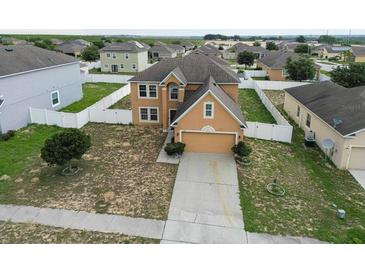 Aerial view of tan two-story home in a residential neighborhood with fenced yards at 2170 Forest Lake Ave, Dundee, FL 33838