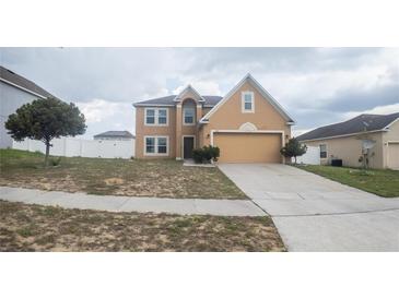 Two-story home with tan exterior, attached garage, and simple landscaping on an overcast day at 2170 Forest Lake Ave, Dundee, FL 33838