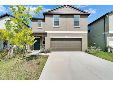 Two-story home with neutral siding, a two-car garage, and a well-maintained lawn at 2244 Teneroc Trl, Lakeland, FL 33801