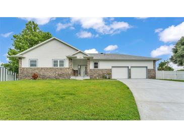 Charming single-story home featuring stone accents, a manicured lawn, and a two-car garage at 535 N Todhunter Way, Lake Alfred, FL 33850