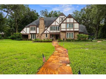 Charming Tudor-style home with a brick facade, lush green lawn, and a stone pathway leading to the front door at 6001 Sweet Gum Run, Bartow, FL 33830