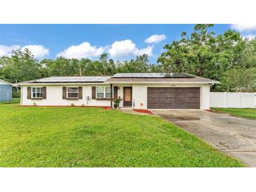 Charming single-story home with a well-maintained lawn, a two-car garage, and modern solar panels at 5316 Forestbrook E Dr, Lakeland, FL 33811