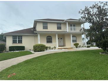 Inviting two-story home with a charming front porch, white railings, and well-maintained landscaping at 5480 Summerland Hills Dr, Lakeland, FL 33812
