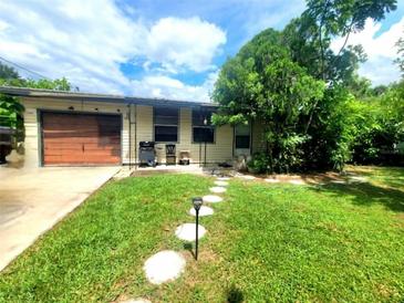 Charming single-story home featuring a well-manicured lawn, stone walkway and attached garage at 722 N Nashua Ave, Fort Meade, FL 33841